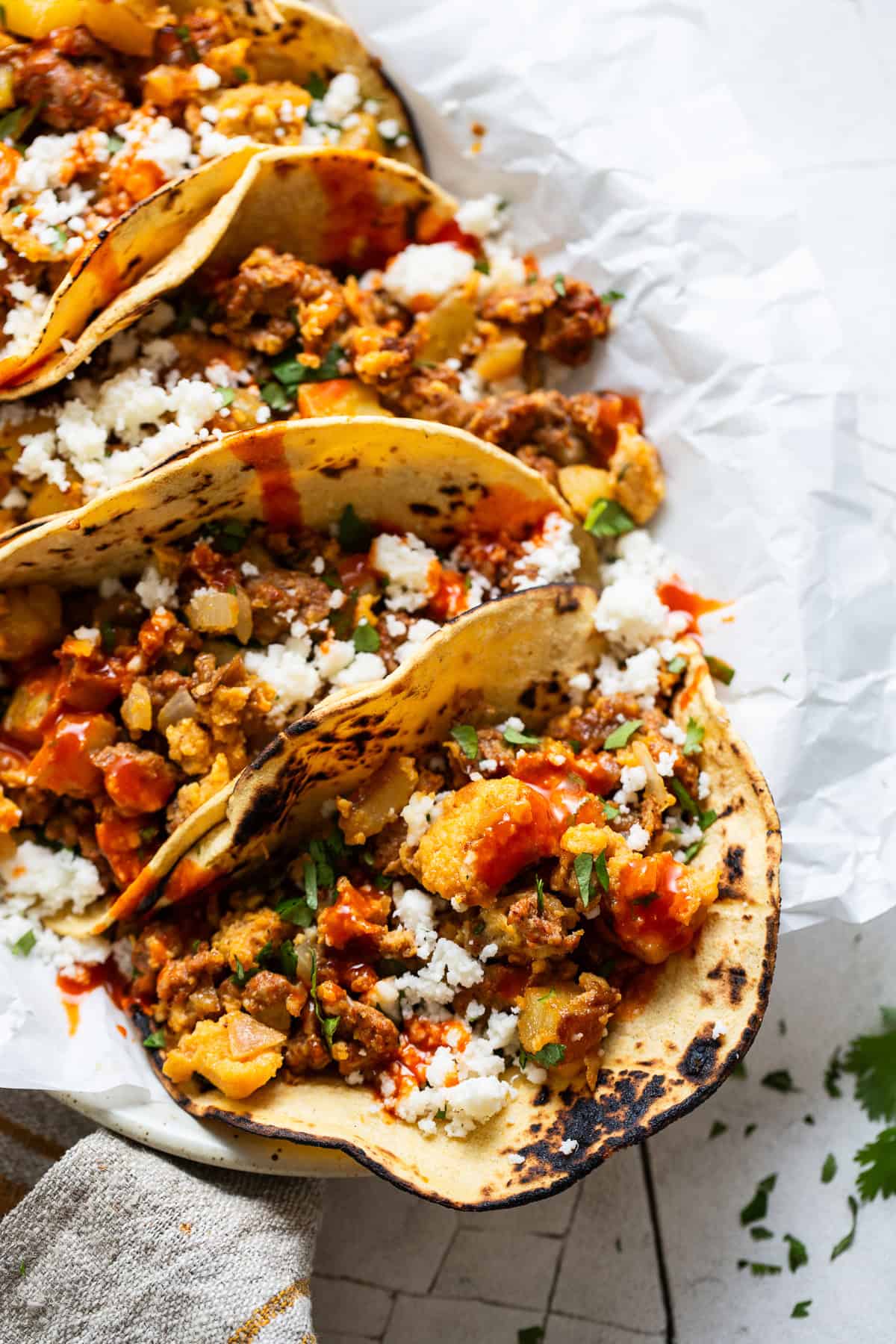 Breakfast tacos served with cilantro, hot sauce, and queso fresco.