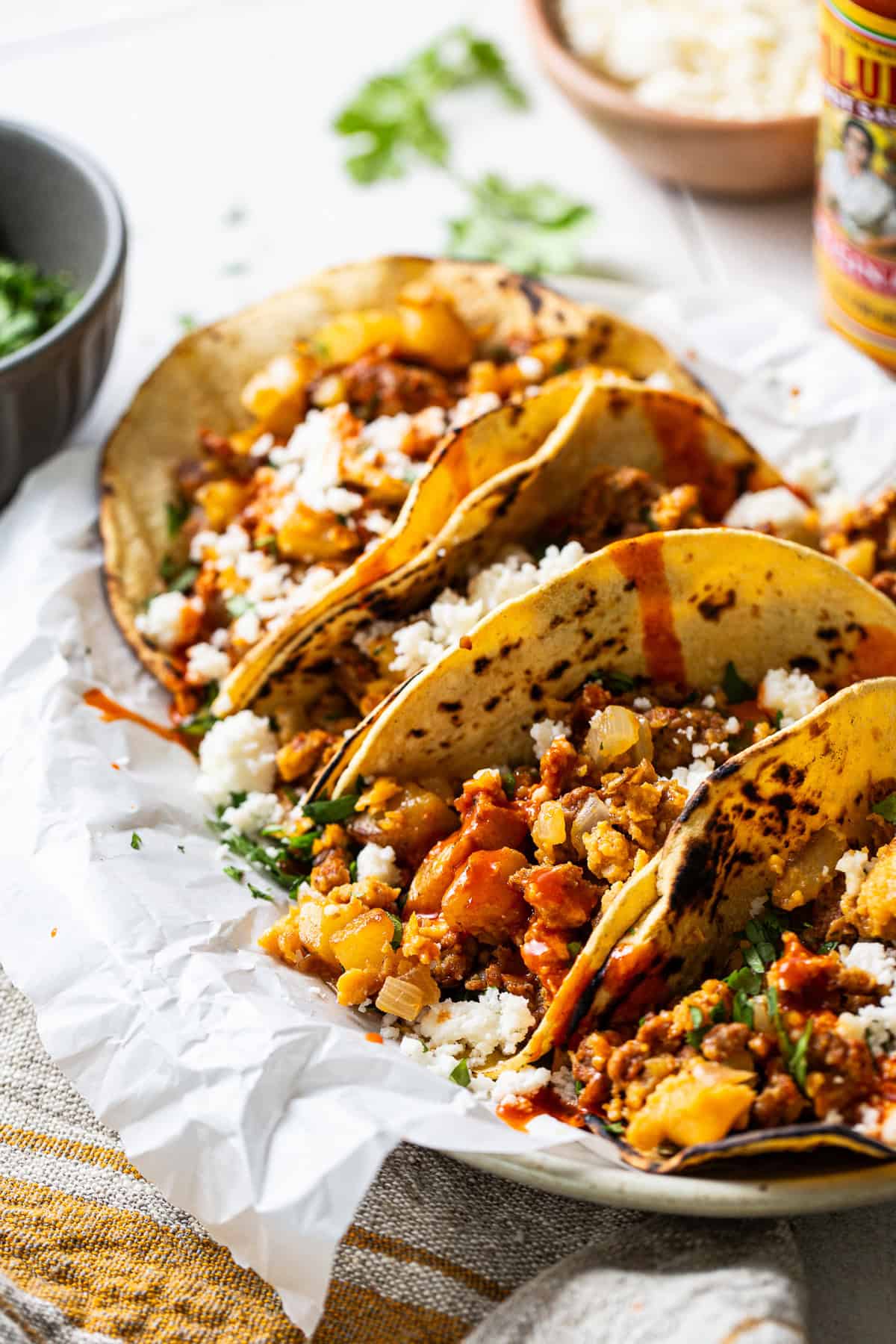 Breakfast tacos plated with hot sauce over top