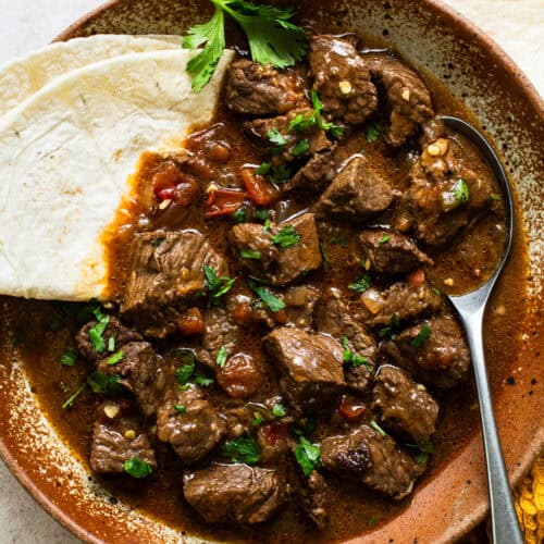 Carne guisada in a bowl with a flour tortilla.