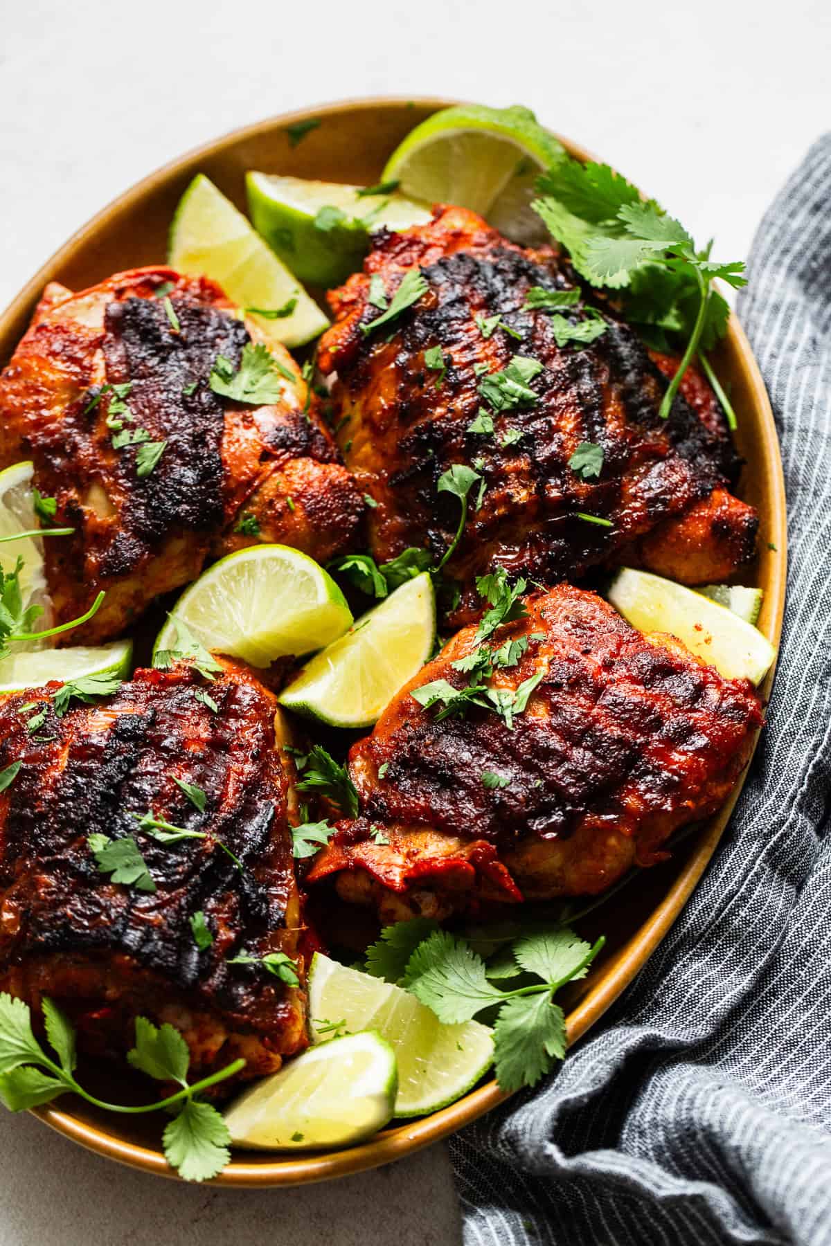 Marinated pollo asado on a serving plate with lime wedges ready to eat.