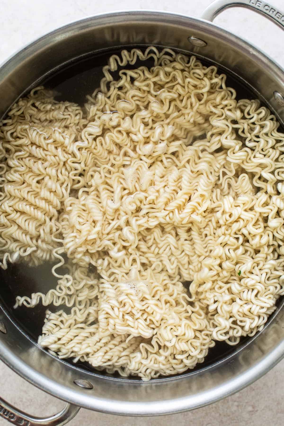 A large pot of water filled with ramen noodles.