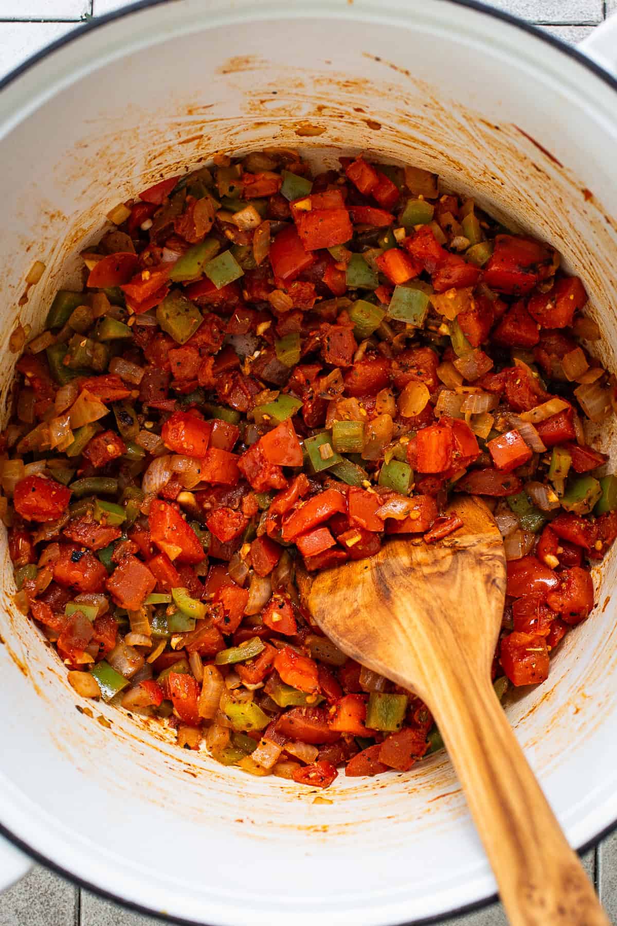 Tomatoes, peppers, and onions cooking in a pot.