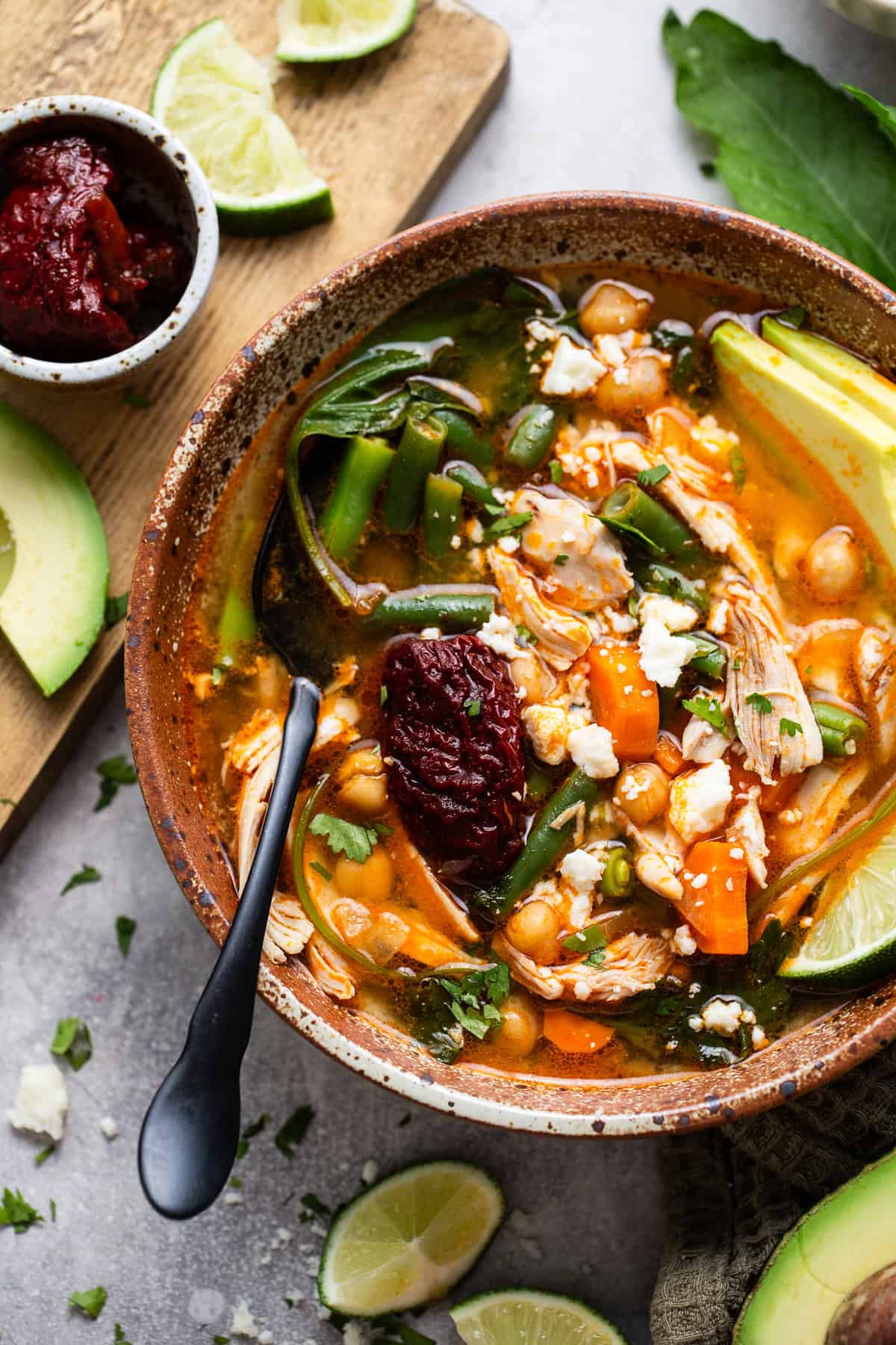 Caldo Tlalpeño garnished with a chipotle pepper in adobo sauce, queso fresco, and cilantro.