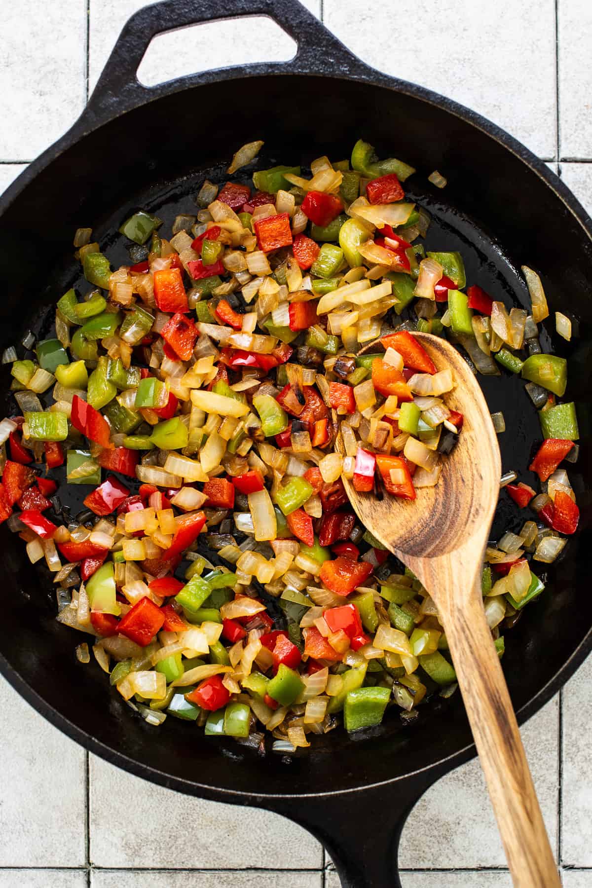 Onions and bell peppers sautéed in a skillet.