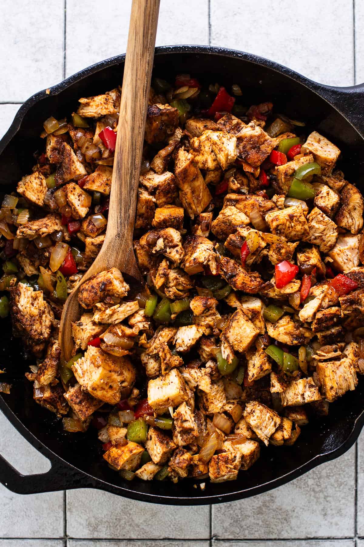 Chicken cooking in a skillet with the vegetables. 