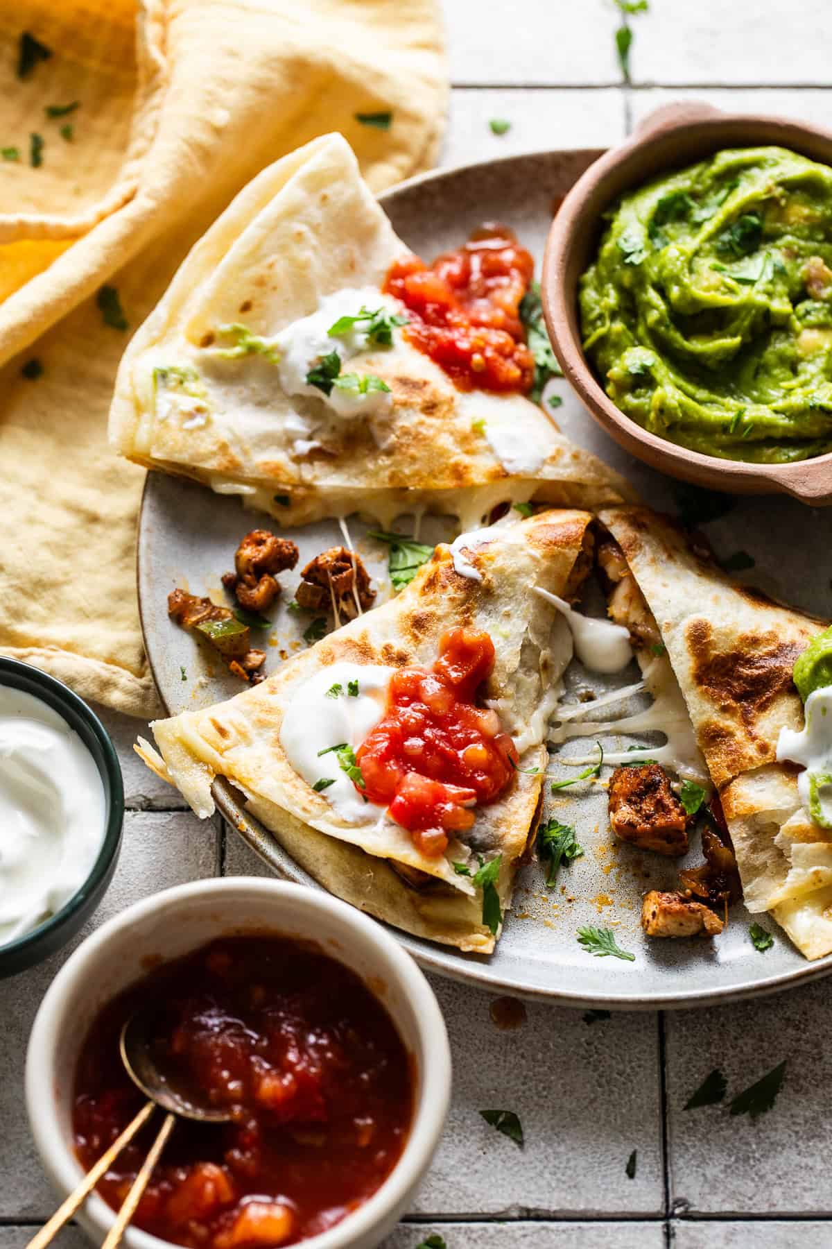 Chicken fajita quesadillas cut into triangles and served on a plate with a side of guacamole.