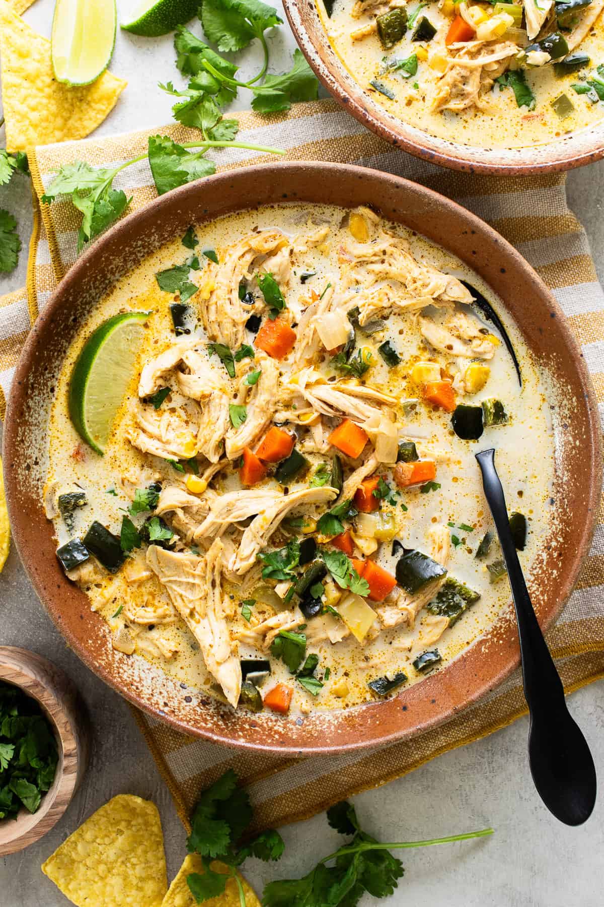 A bowl filled with warm chicken poblano soup garnished with cilantro and lime juice.