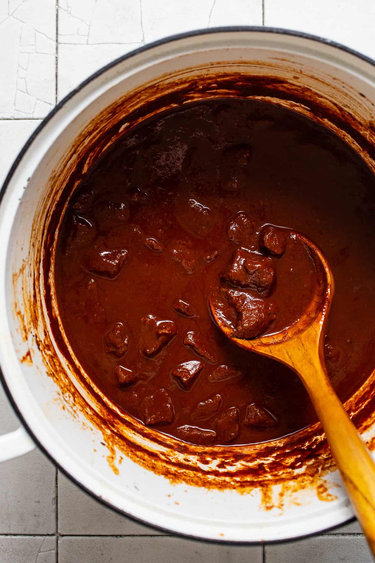 Authentic Mexican chile colorado in a pot with a wooden spoon ready to serve.