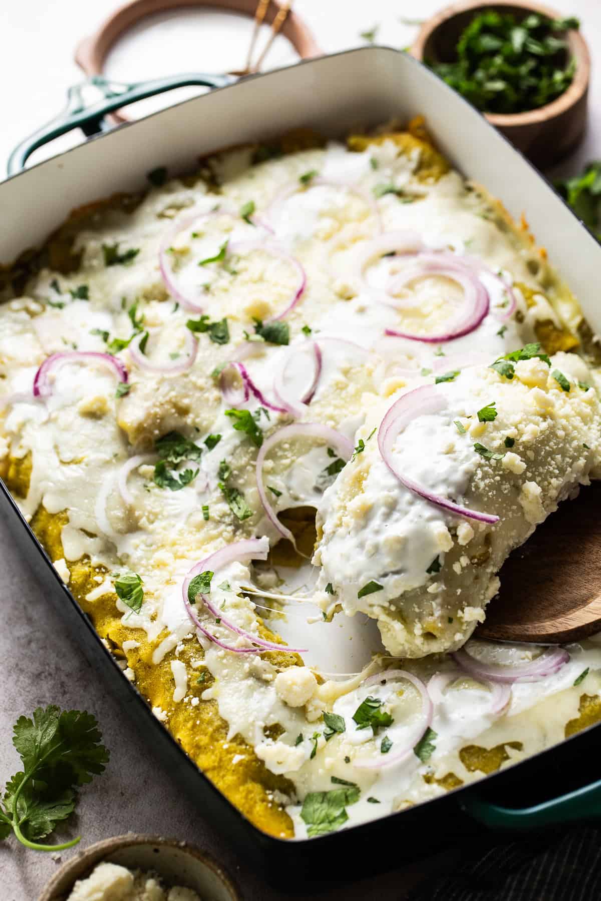 Ready to eat enchialdas verdes with sour cream, cilantro,, and red onions. 