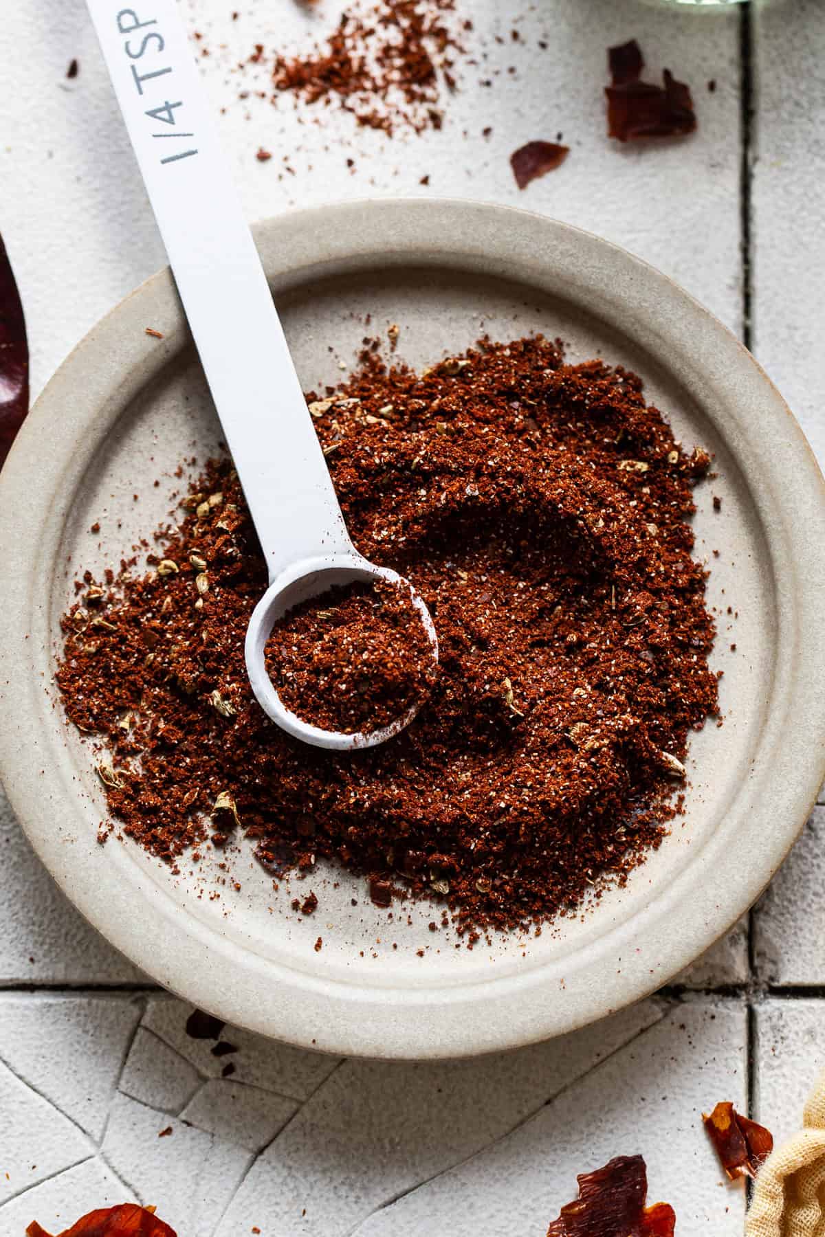 Homemade chili powder on a plate with a measuring spoon ready to be used in various recipes.