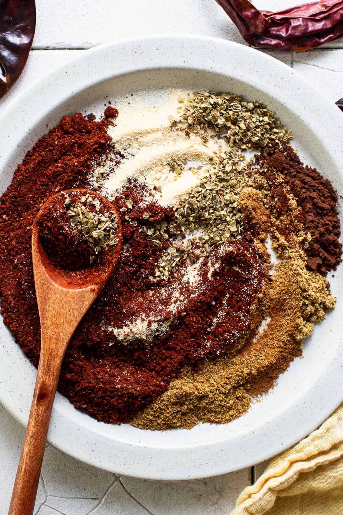 Chili powder and other spices in a bowl before being mixed and combined to make homemade chili powder.