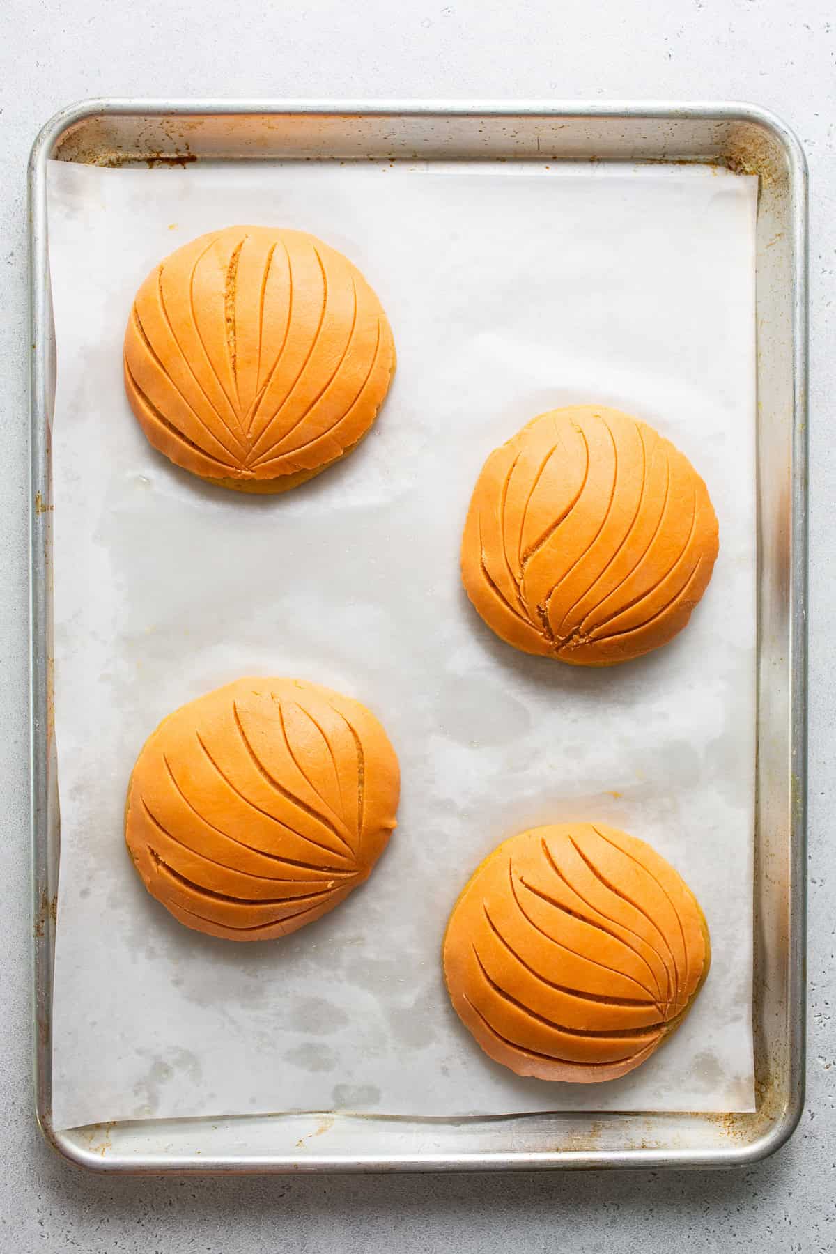 Pumpkin conchas with an orange streusel topping on top that have little indents to make it look like a clamshell.