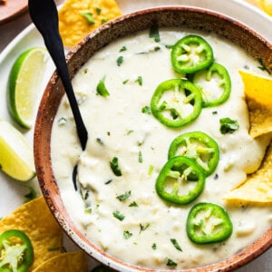 Salsa Verde Queso dip in a bowl served with tortilla chips.