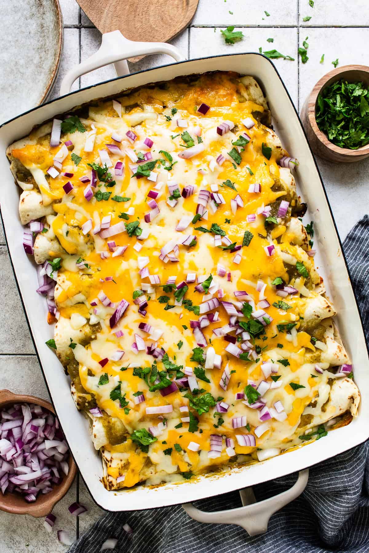 Baked spinach enchiladas topped with cheese and red onions ready to enjoy! 