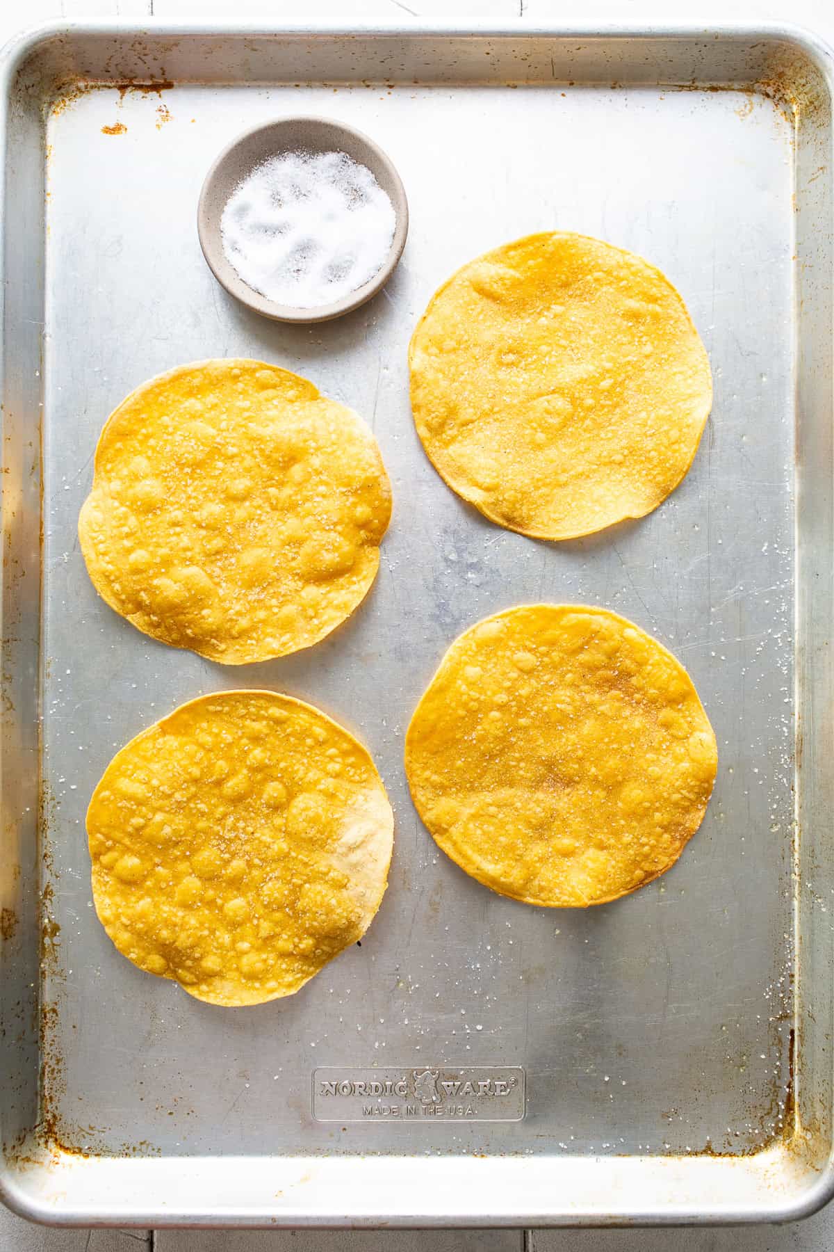 Baked corn tortillas on a baking sheet.