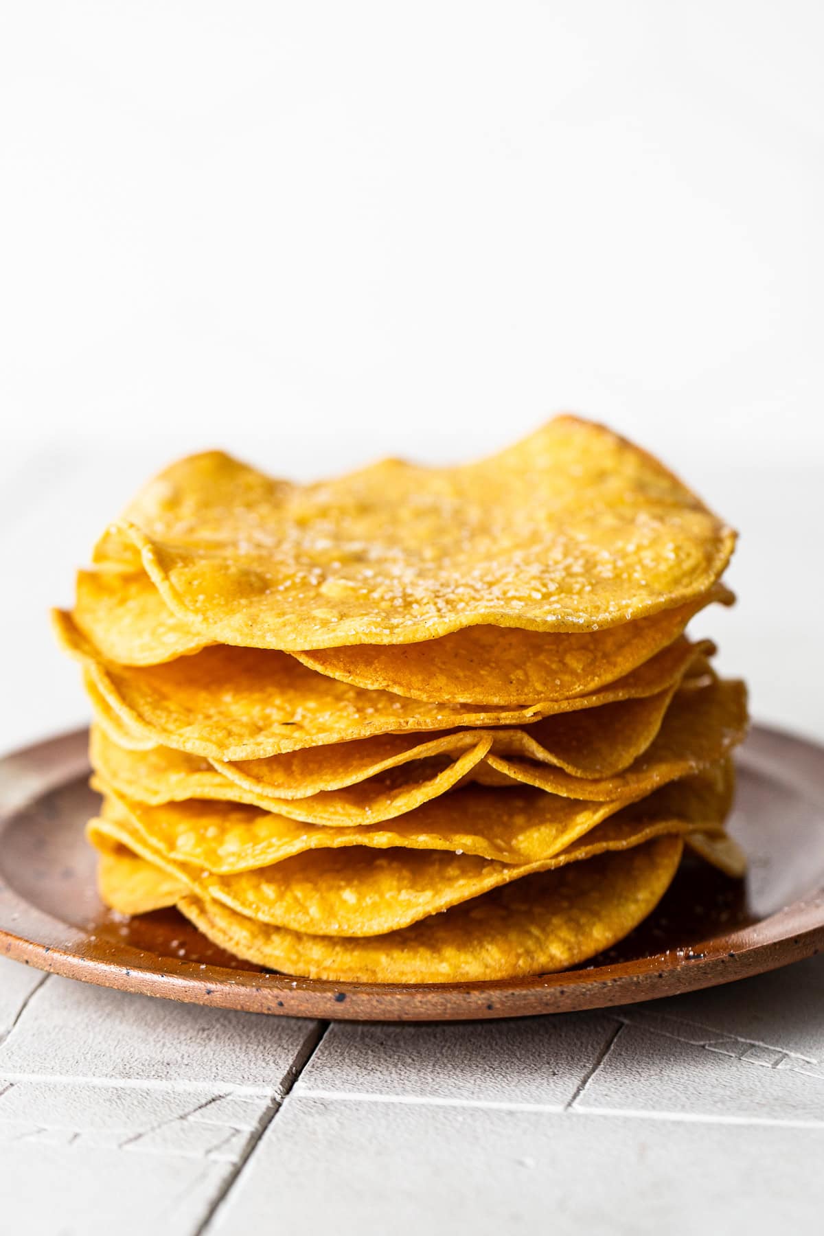 Homemade tostada shells baked and ready to eat on a plate.