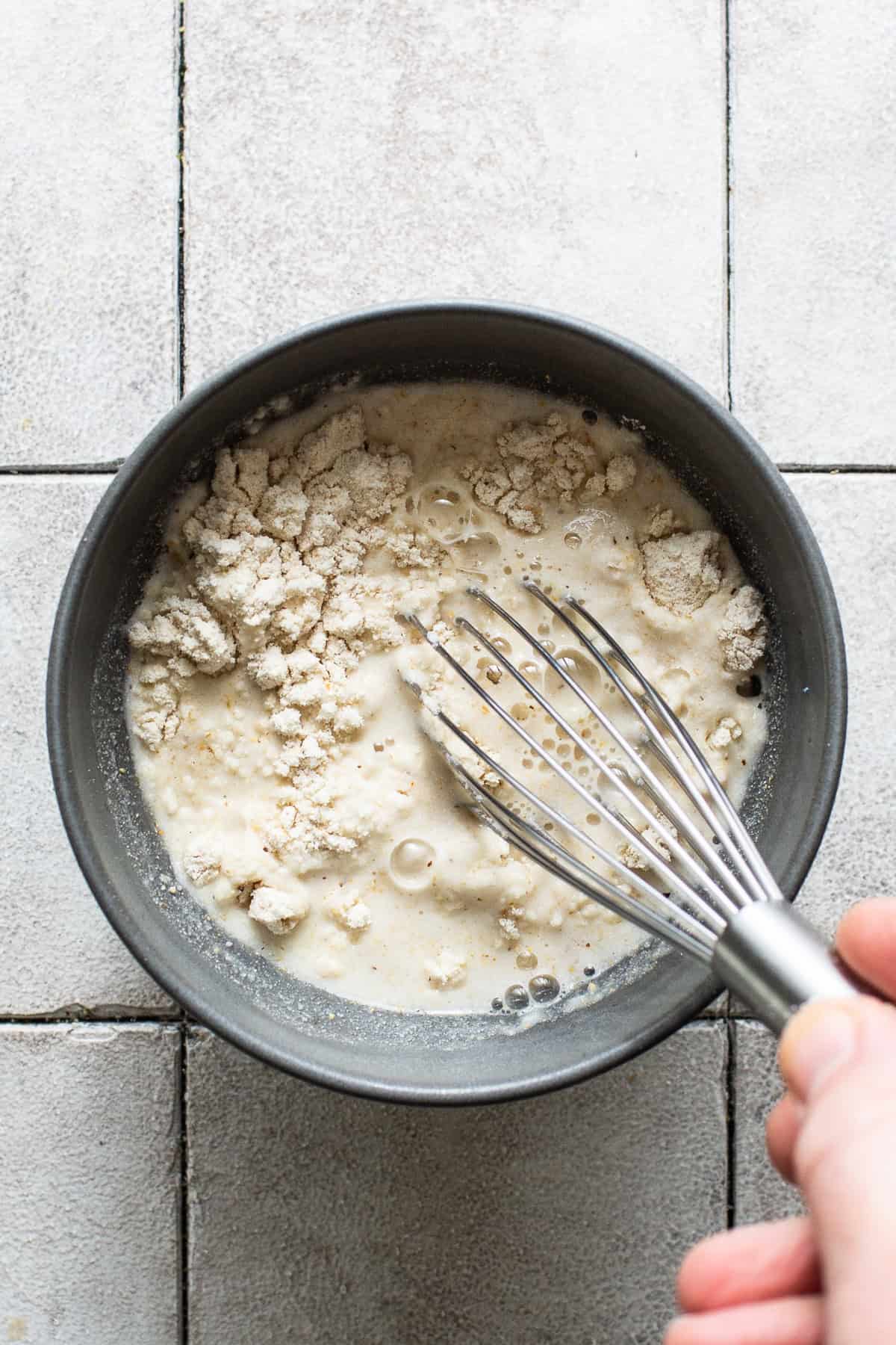 Masa harina and water being whisked in a bowl.