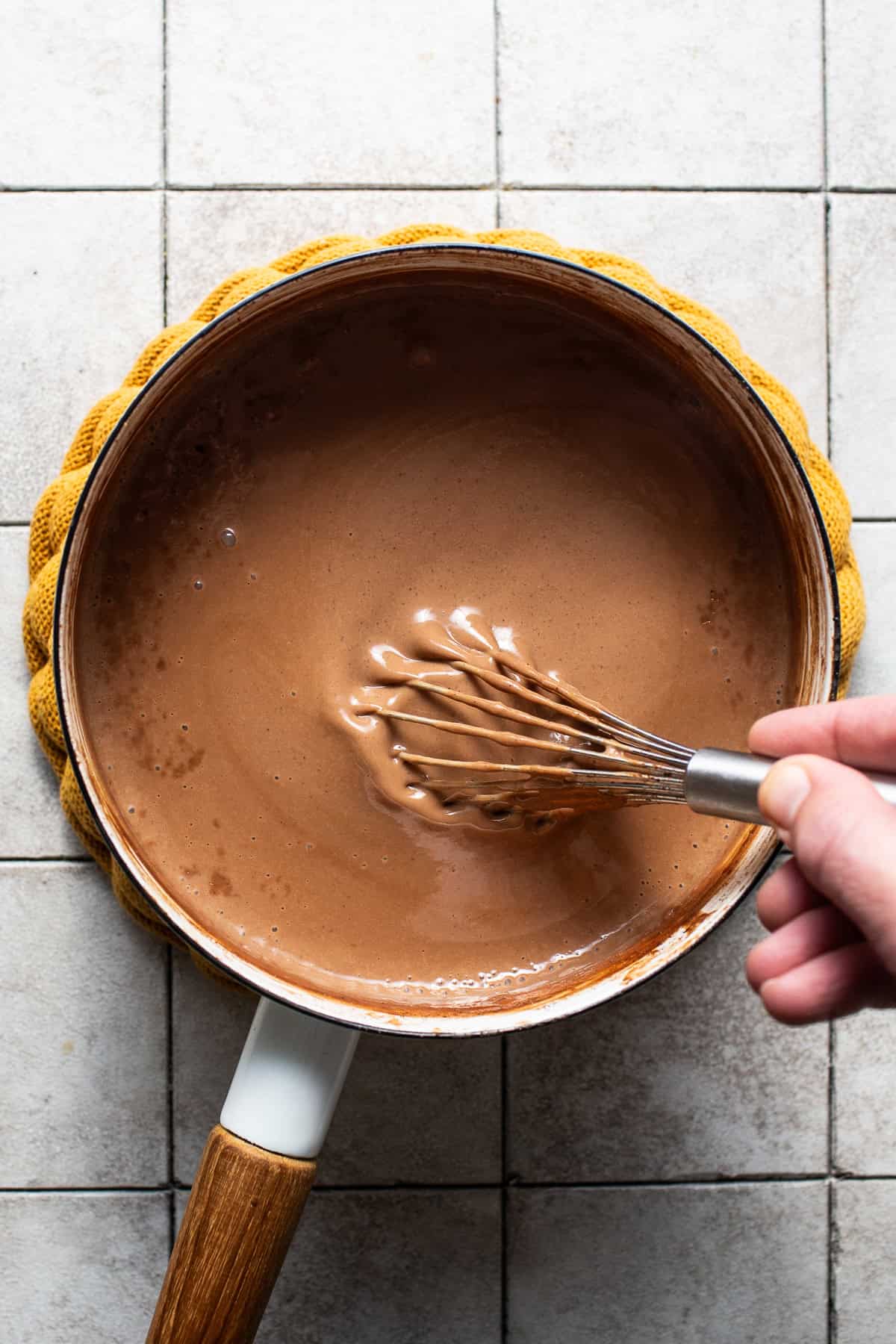 Thick champurrado being whisked together in a saucepan.