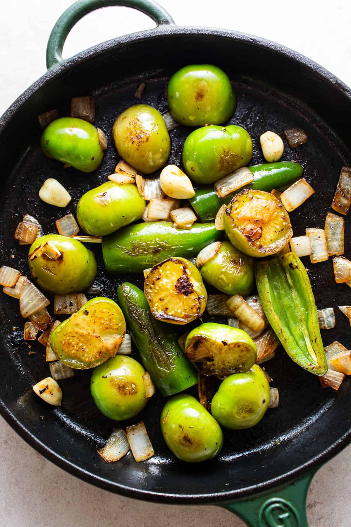 Skillet with tomatillos, jalapeños, onions, and garlic being caramelized.