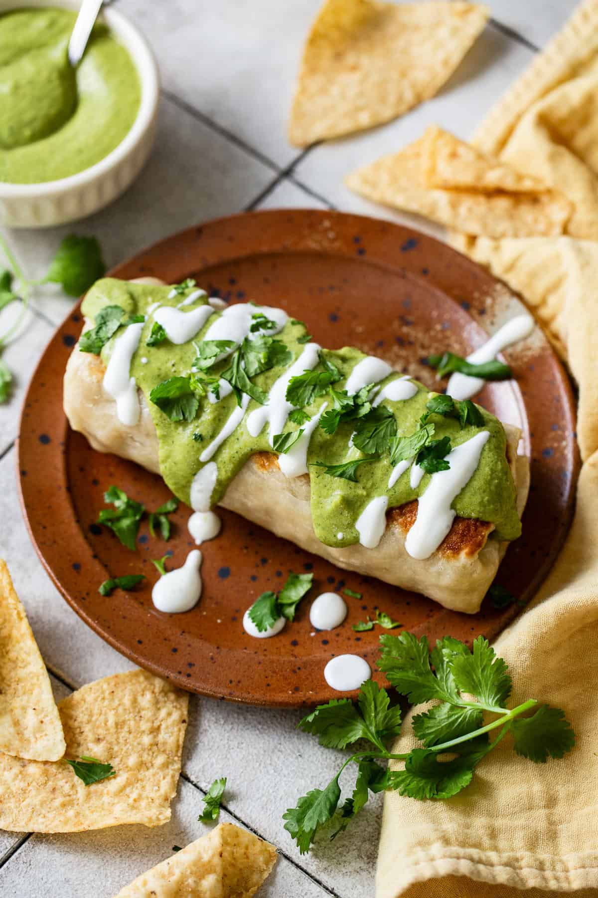 A chimichanga topped with poblano cream sauce and Mexican crema.