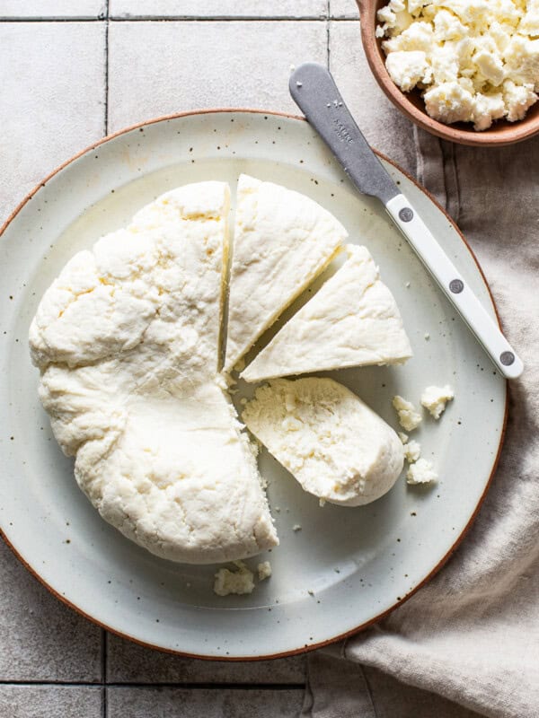 A homemade queso fresco recipe on a plate cut into wedges ready to eat and be sprinkled on Mexican food.