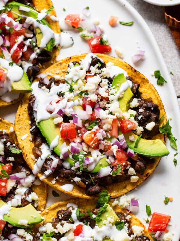 Black bean tostadas topped with avocado, cilantro, tomatoes, and sour cream.