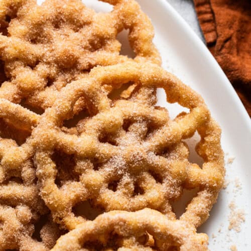 Buñuelos de Viento on a plate covered in cinnamon sugar.