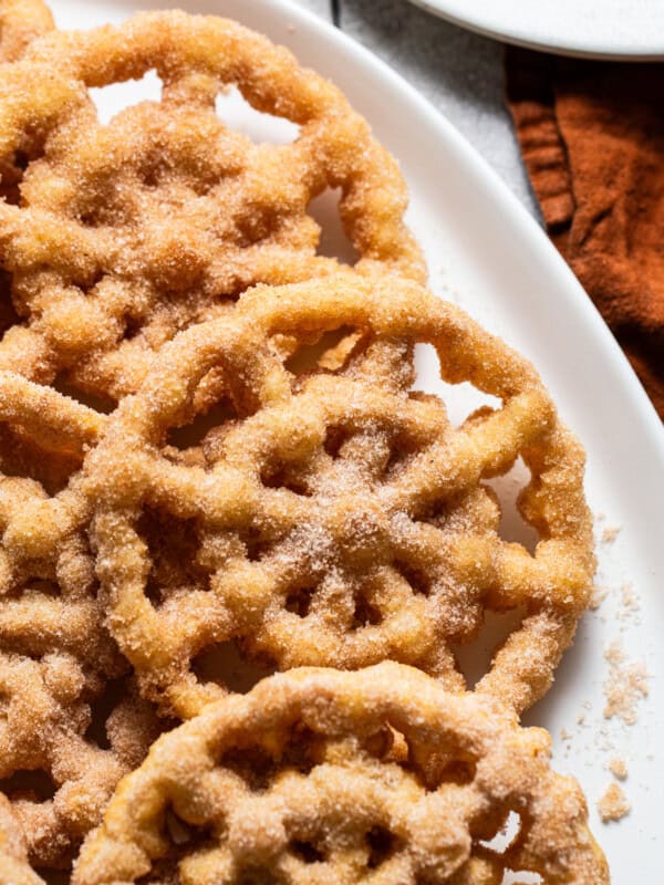 Buñuelos de Viento on a plate covered in cinnamon sugar.