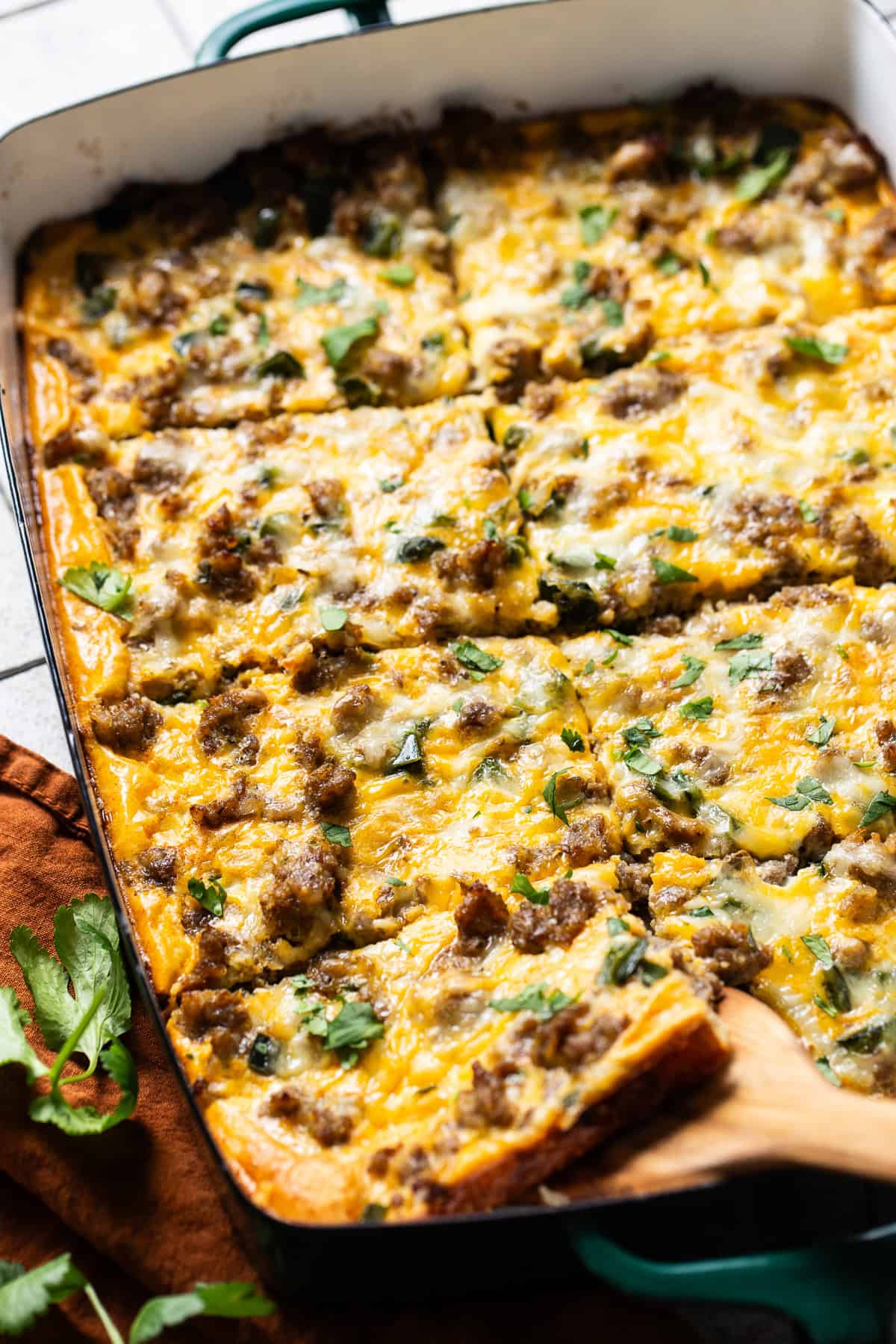 A slice of crescent roll breakfast casserole being removed from a baking dish with a wooden spatula.