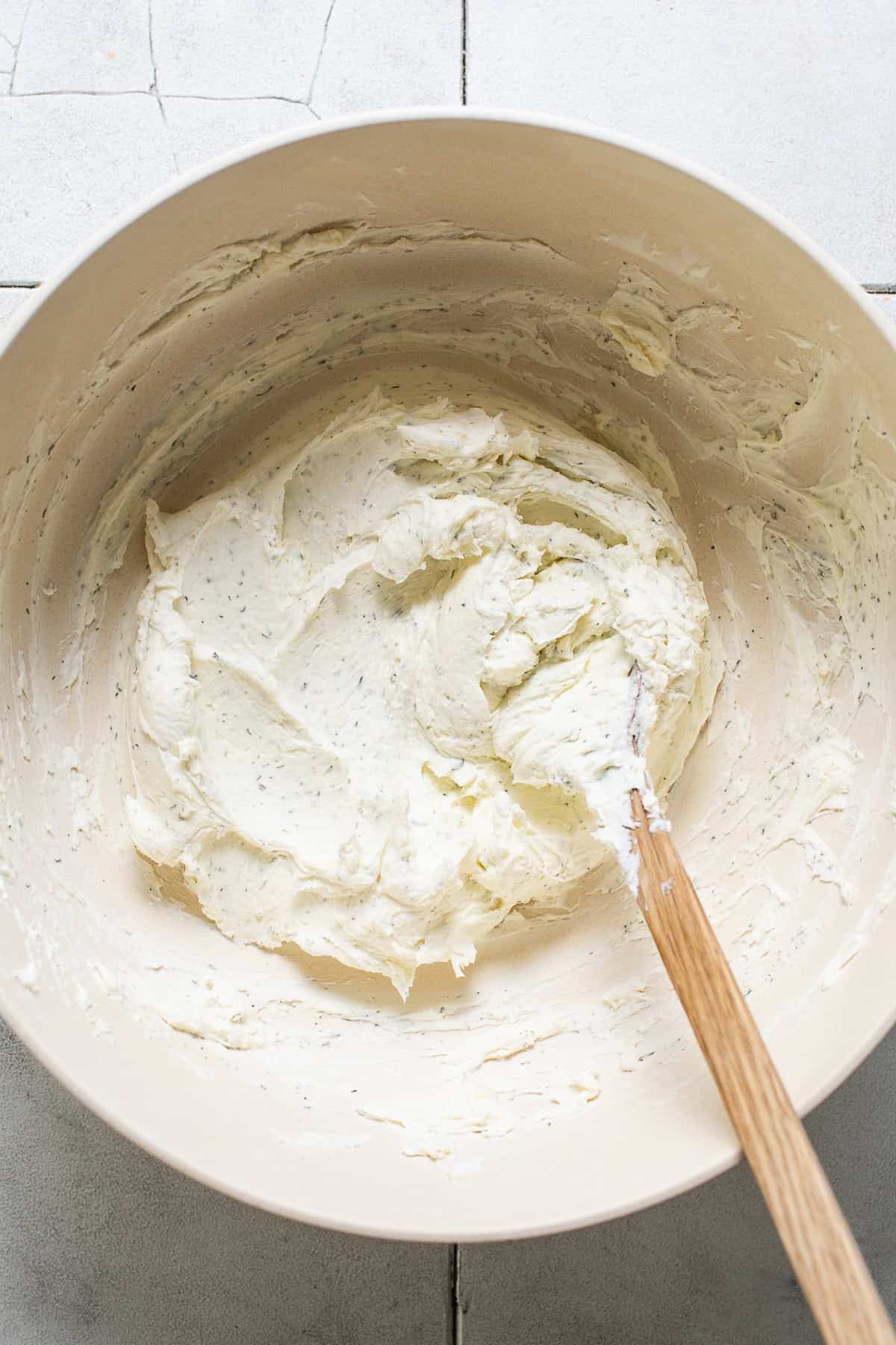 Cream cheese, sour cream and seasonings mixed together in a bowl to create a cheese ball.