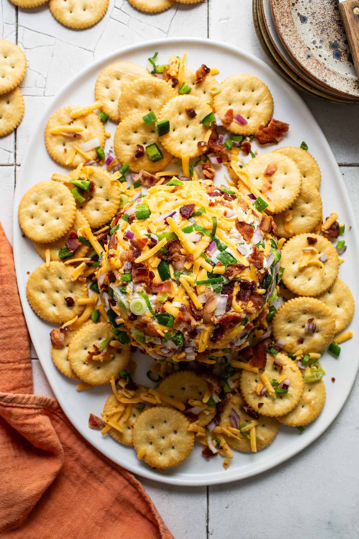 A ball of jalapeño cheese on a serving platter next to Ritz crackers ready to eat.