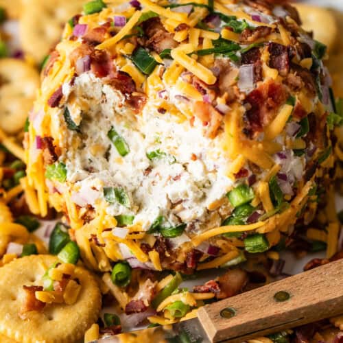 A simple ball of jalapeño cheese covered in bacon and cheddar on a plate with crackers.