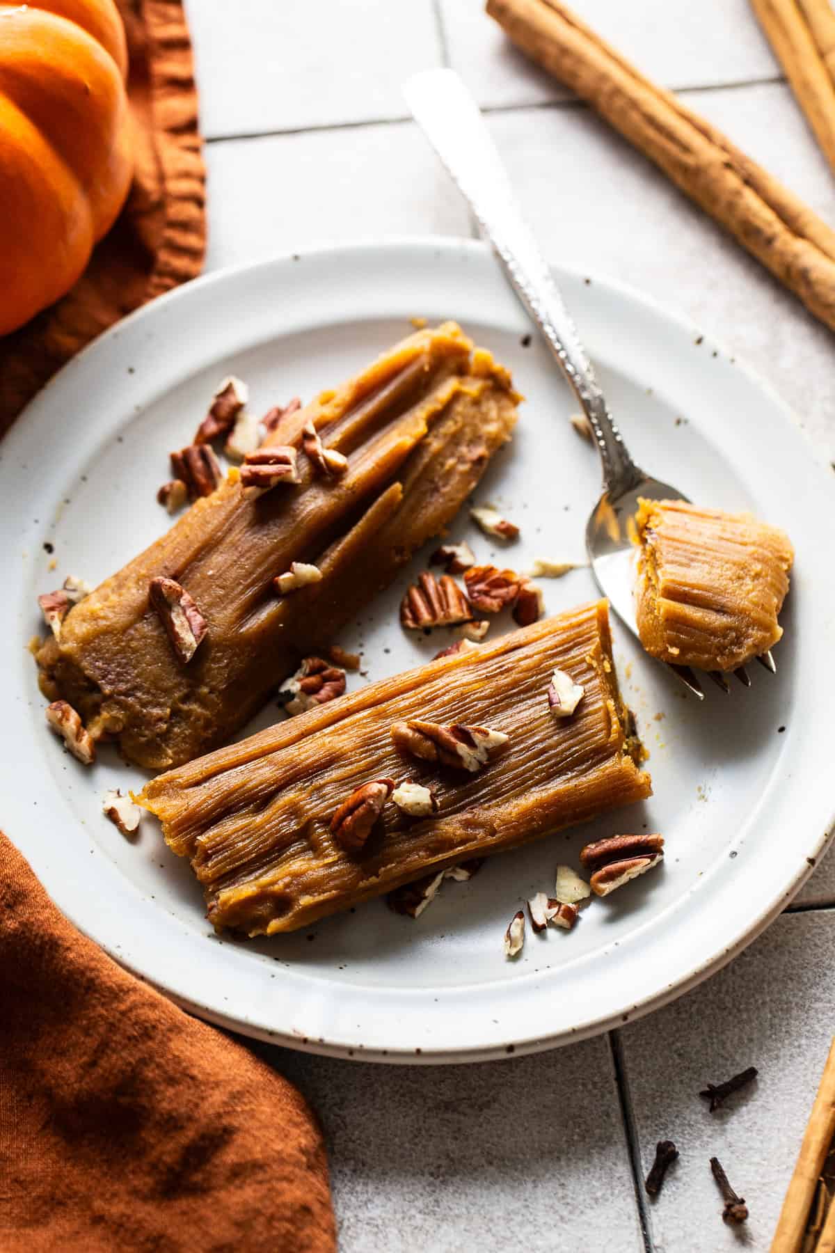 Pumpkin tamales on a plate garnished with chopped pecans.