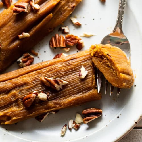 Pumpkin tamales on a plate garnished with some chopped pecans.