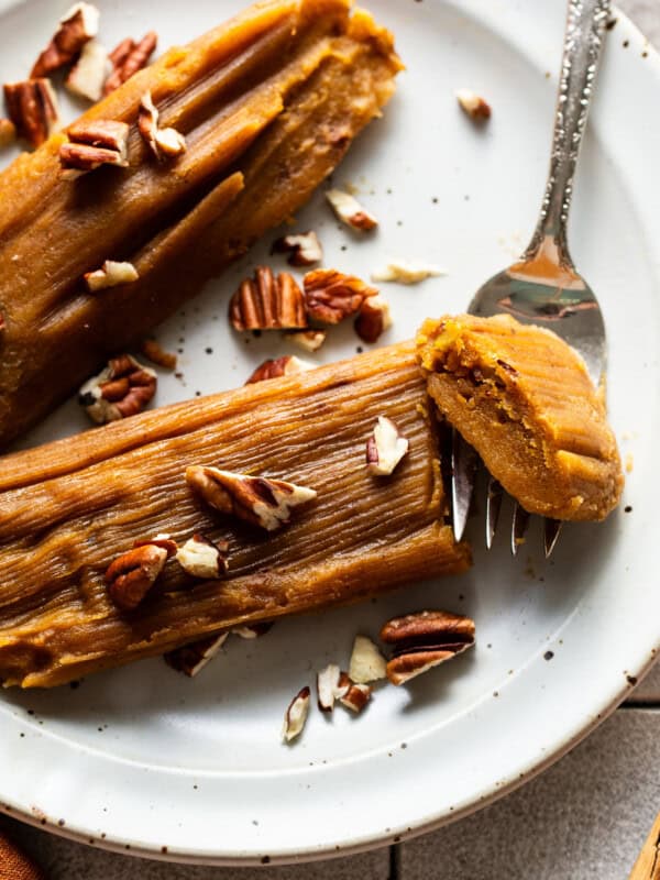 Pumpkin tamales on a plate garnished with some chopped pecans.