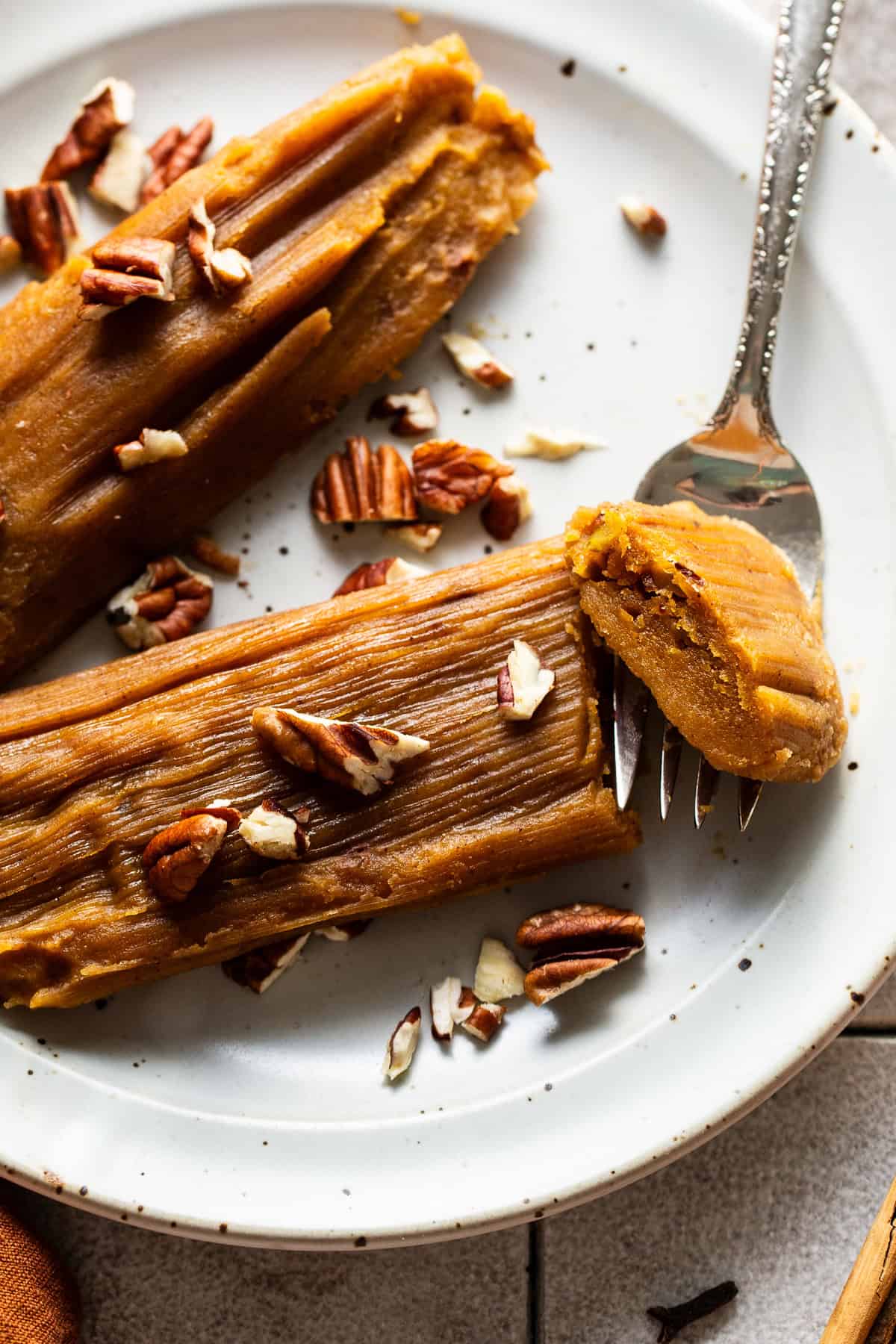 Pumpkin tamales on a plate garnished with some chopped pecans.