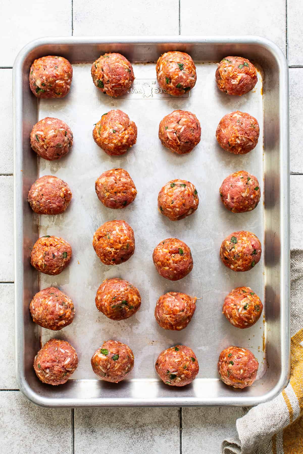 24 formed meatballs on a baking sheet ready to be cooked for mexican albondigas soup.