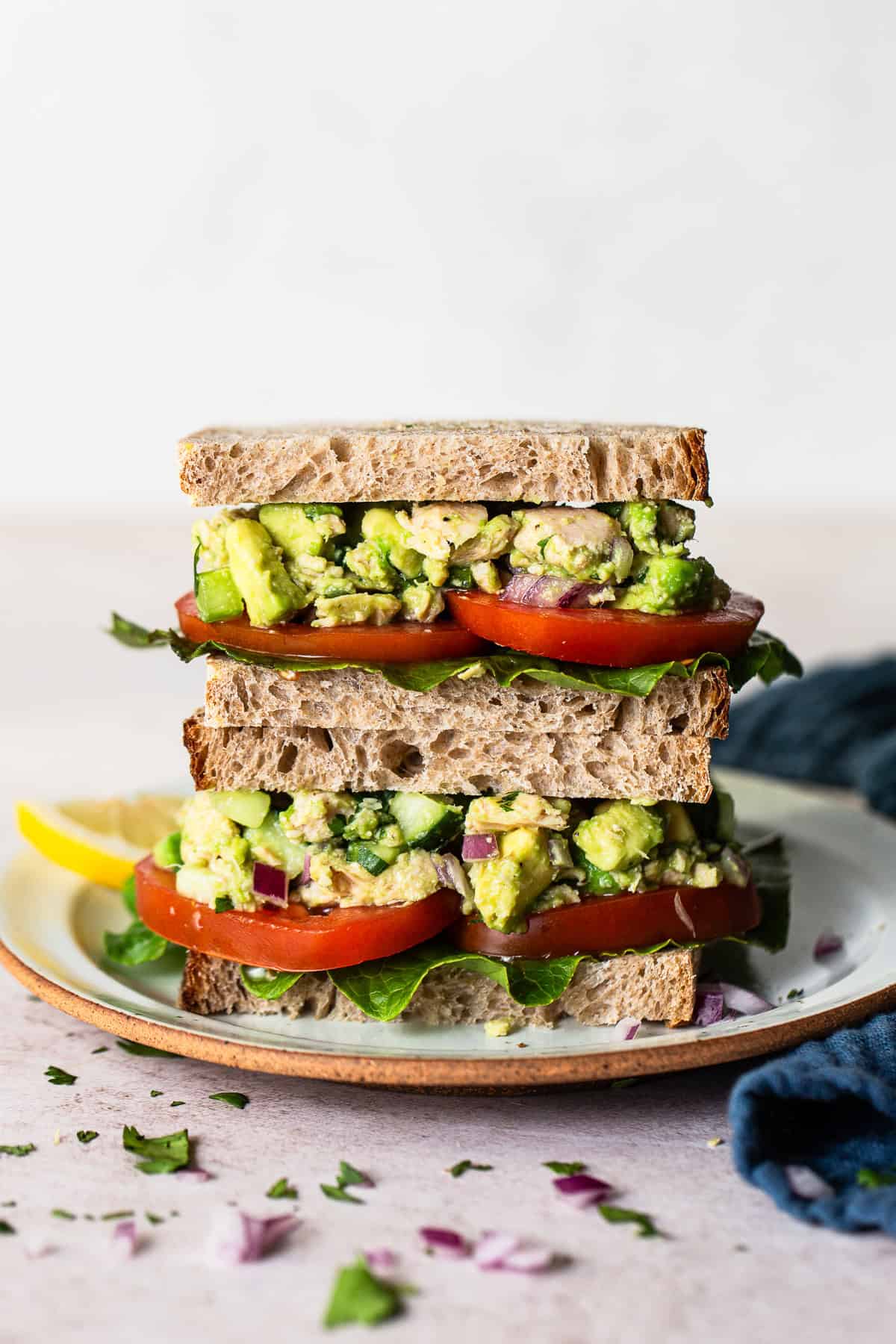 A avocado tuna salad sandwiched cut in half and placed on a  plate to view the filling. 