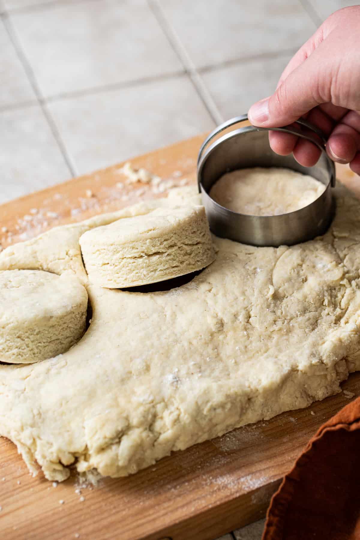 Masa harina biscuits being cut out with a biscuit cutter on a floured surface.