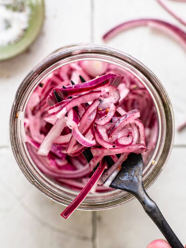 Mexican pickled onions in a glass jar on a fork ready to be eaten.