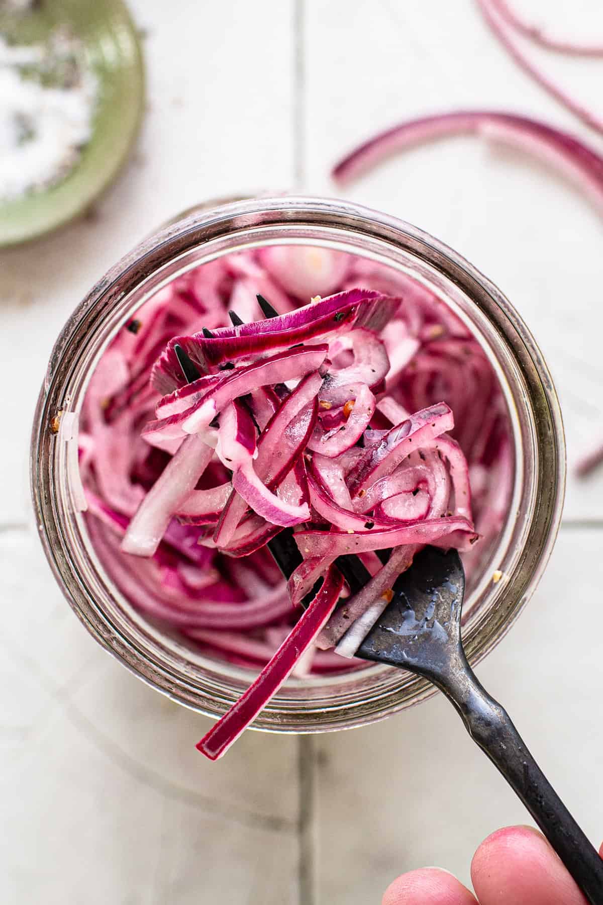 Mexican pickled onions in a glass jar on a fork ready to be eaten.