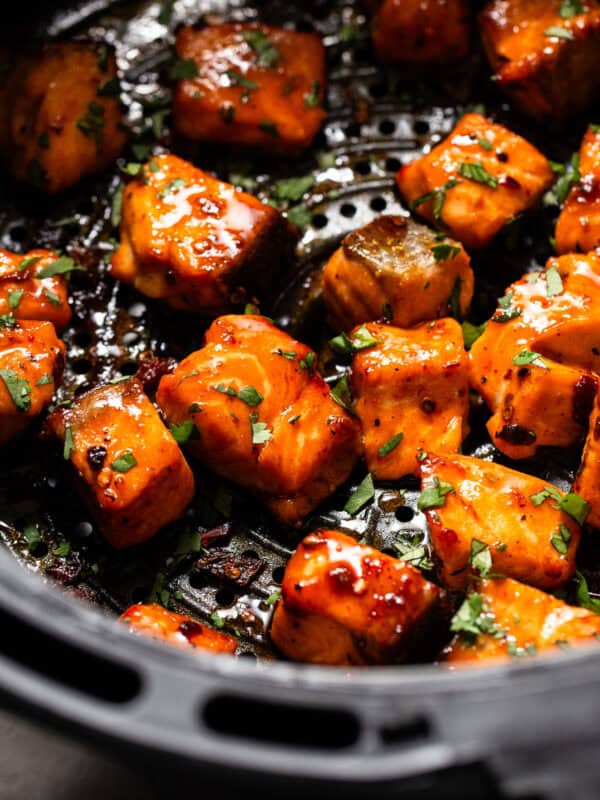 Air fryer salmon bites in an air fryer basket tossed in a chipotle honey sauce.