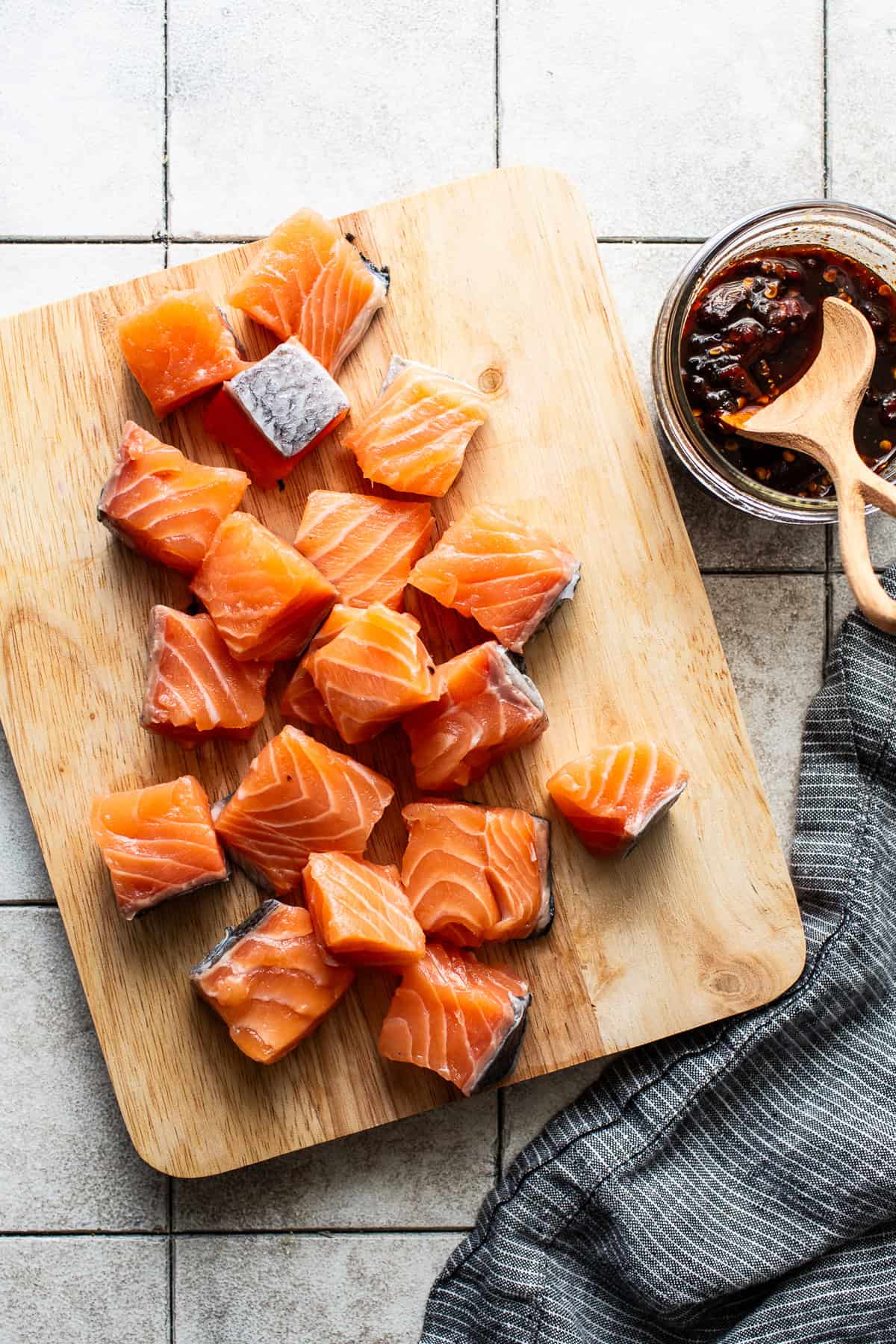 Salmon cut into 1-inch cubes on a cutting board.