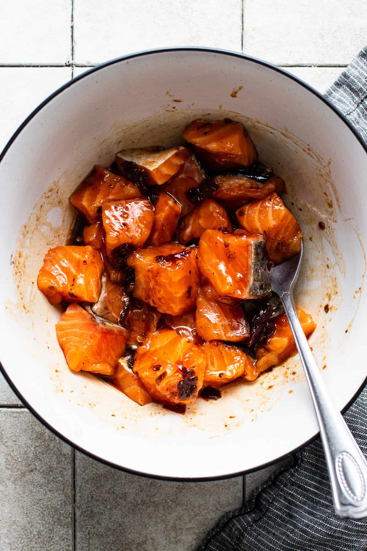 Salmon bites tossed in a honey chipotle sauce in a small bowl.