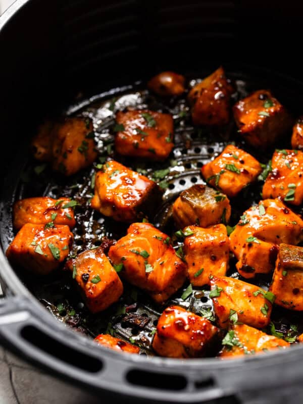 Air fryer salmon bites in an air fryer basket tossed in a chipotle honey sauce.