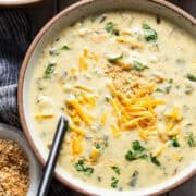 Creamy chile relleno soup in a bowl topped with cilantro and shredded cheese.