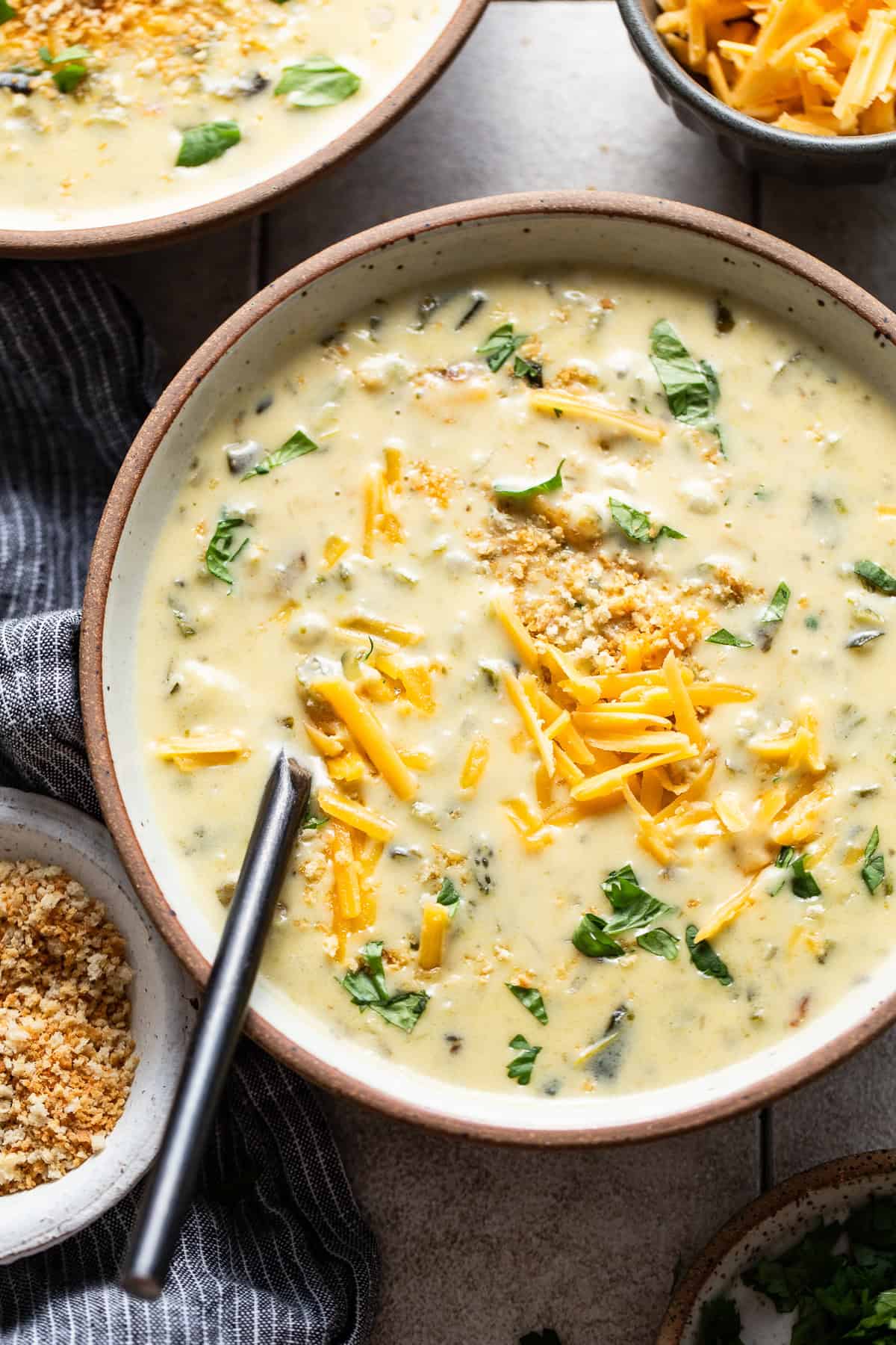 Creamy chile relleno soup in a bowl topped with cilantro and shredded cheese.