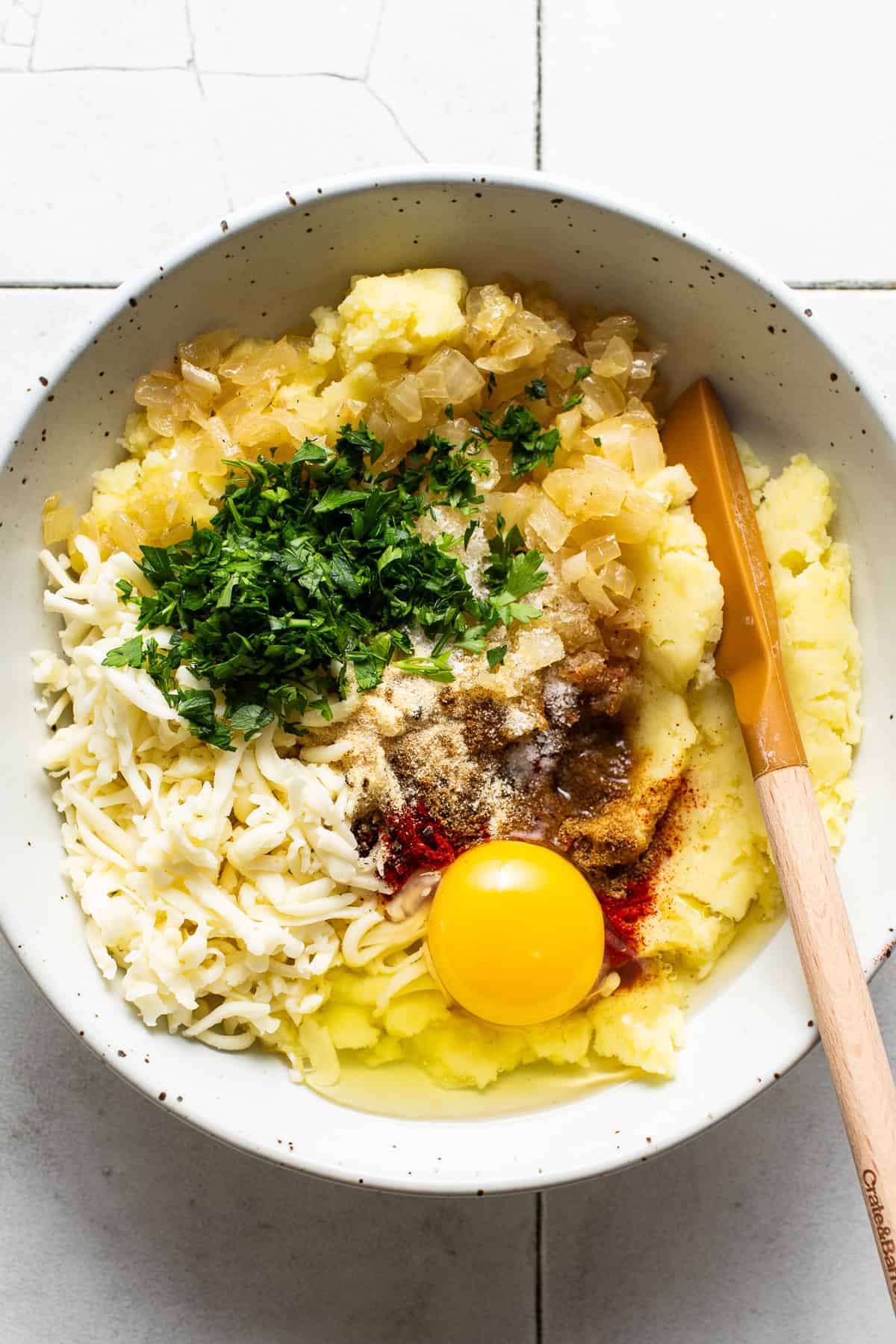 A mixing bowl filled with potato mixture ingredients.