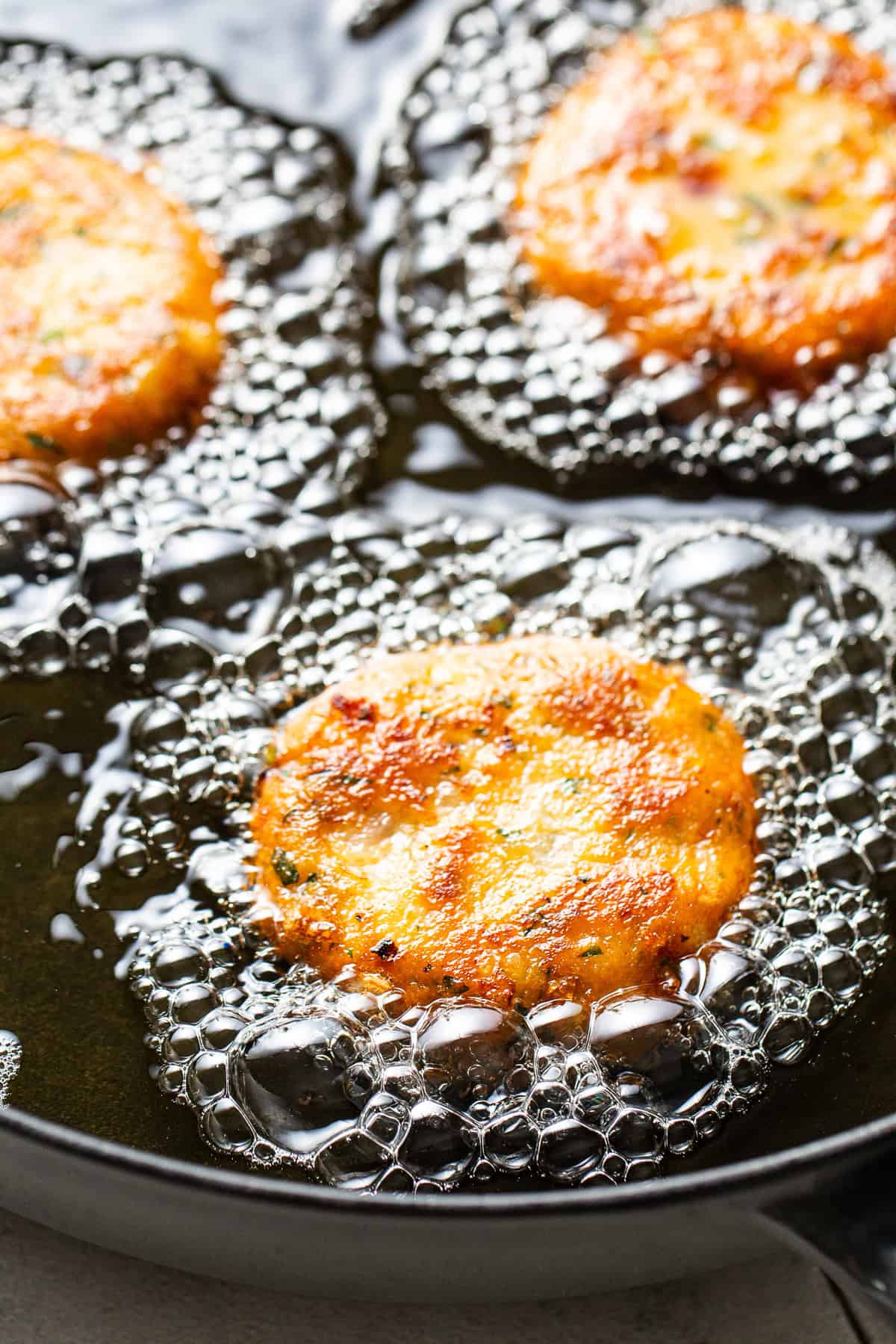 In a shallow skillet the tortitas de papa are frying.