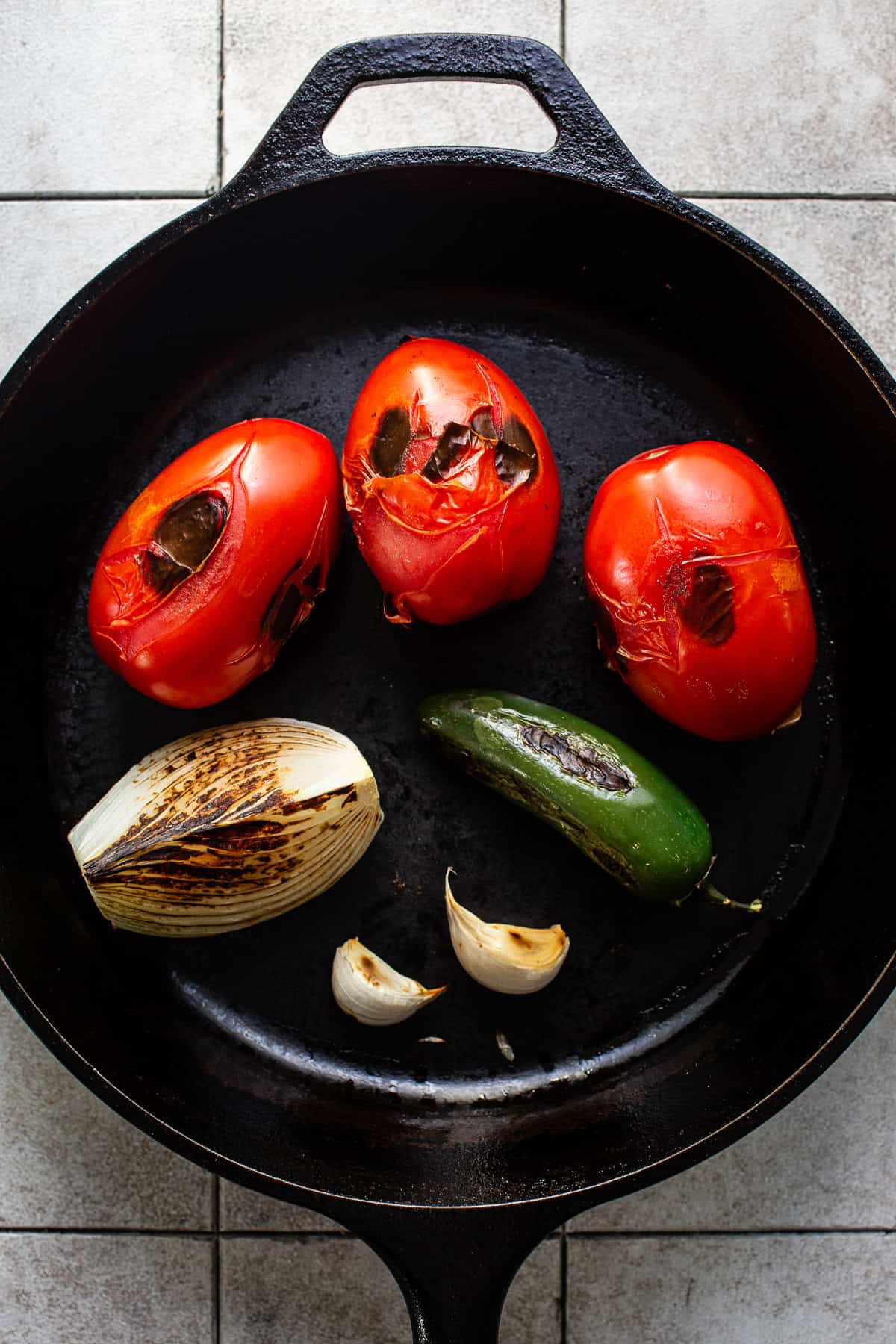 Dry roasted tomatoes, onion, jalapeno, and garlic in a cast iron pan.